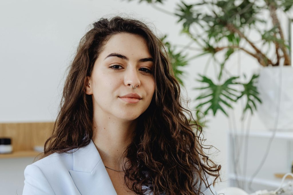 Portrait of a confident young woman in an office setting with urban greenery.